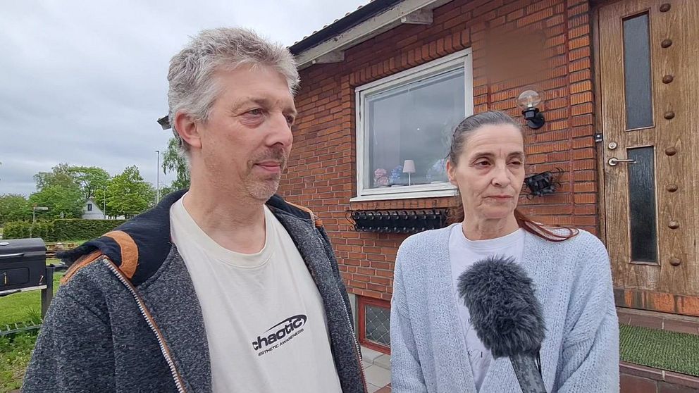 Två personer intervjuas med mikrofon utanför ett rött tegelhus i Klippan efter det misstänkta dubbelmordet.