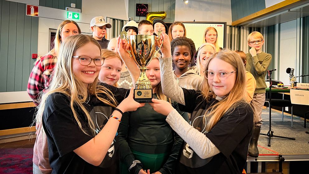 Två femteklassare håller upp en guldpokal framför sin klass och alla ser glada ut.