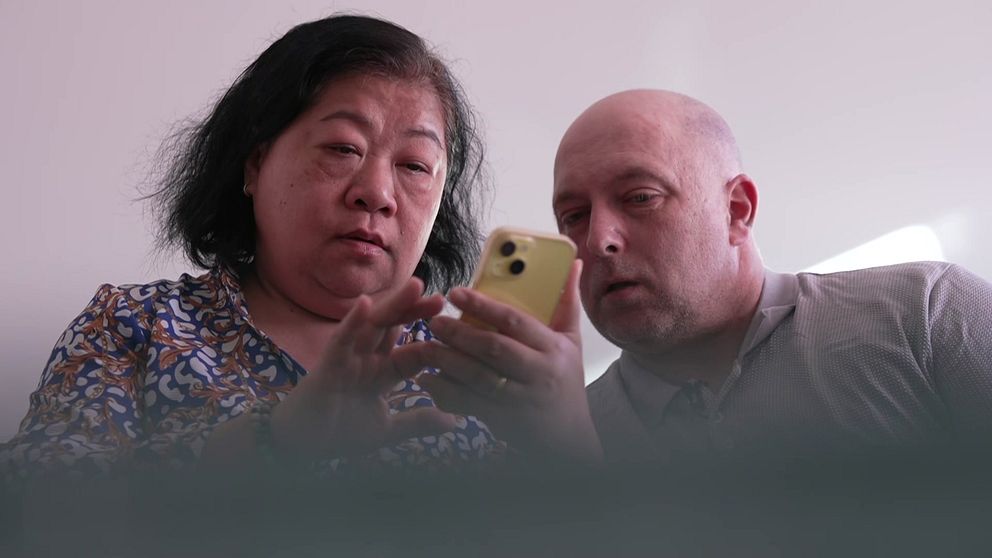 Två personer tittar tillsammans på en mobiltelefon.