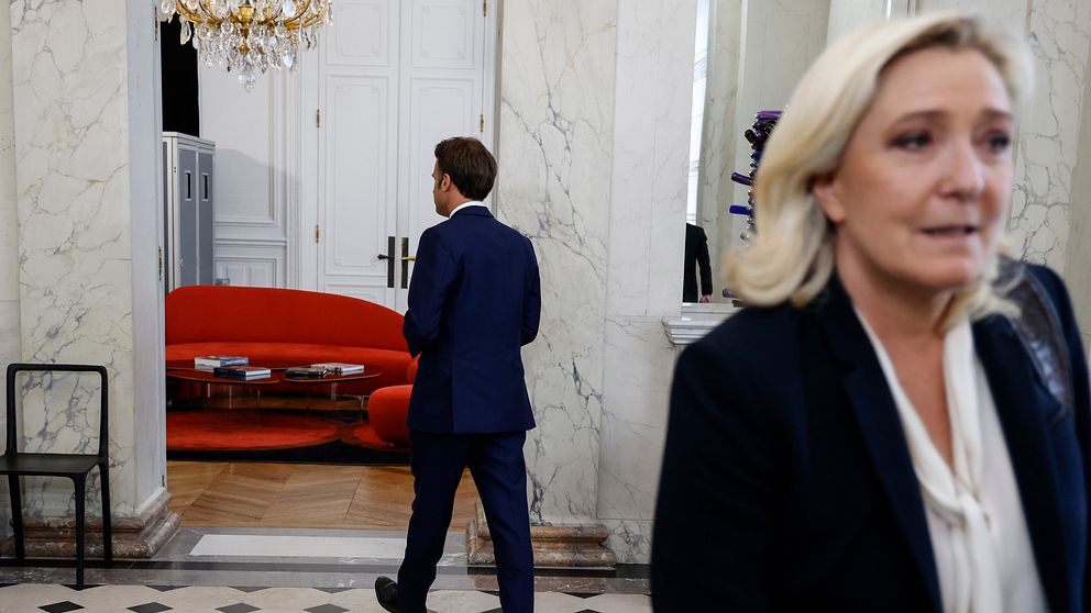 Presidens Emmanuel Macron lämnar ett rum samtidigt som Marine le Pen.