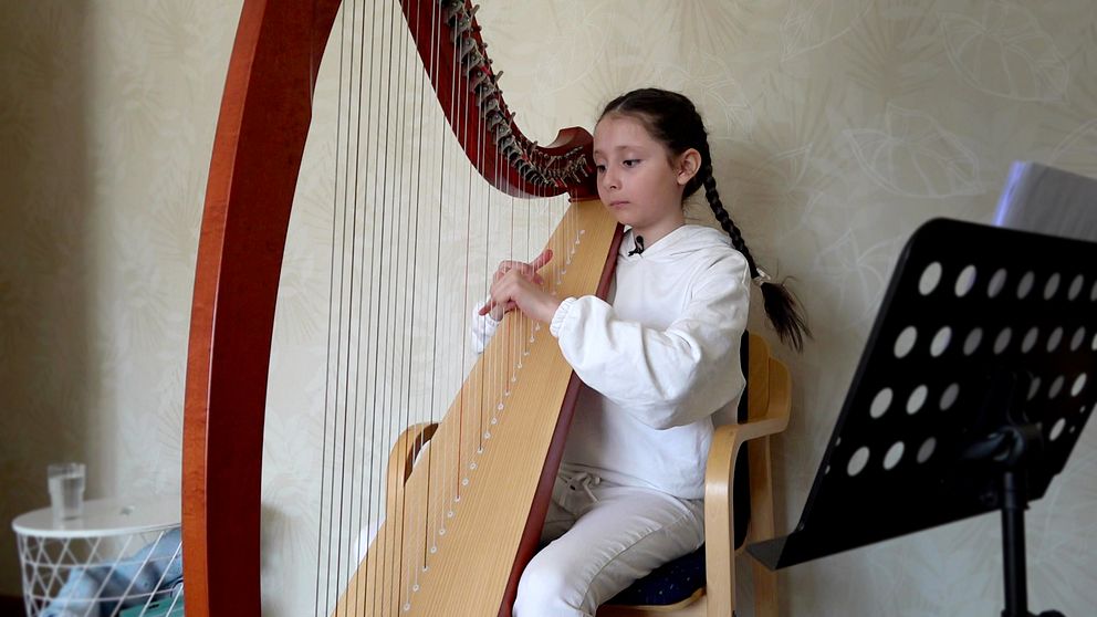 Diana Pyliavska, 9 år, sitter vid sin harpa i bostaden i Luleå.