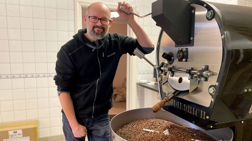 Person rostar kaffebönor i en stor rostningsmaskin.