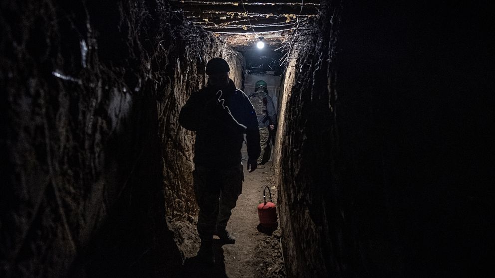 Person går genom en mörk tunnel med svagt ljus i bakgrunden.