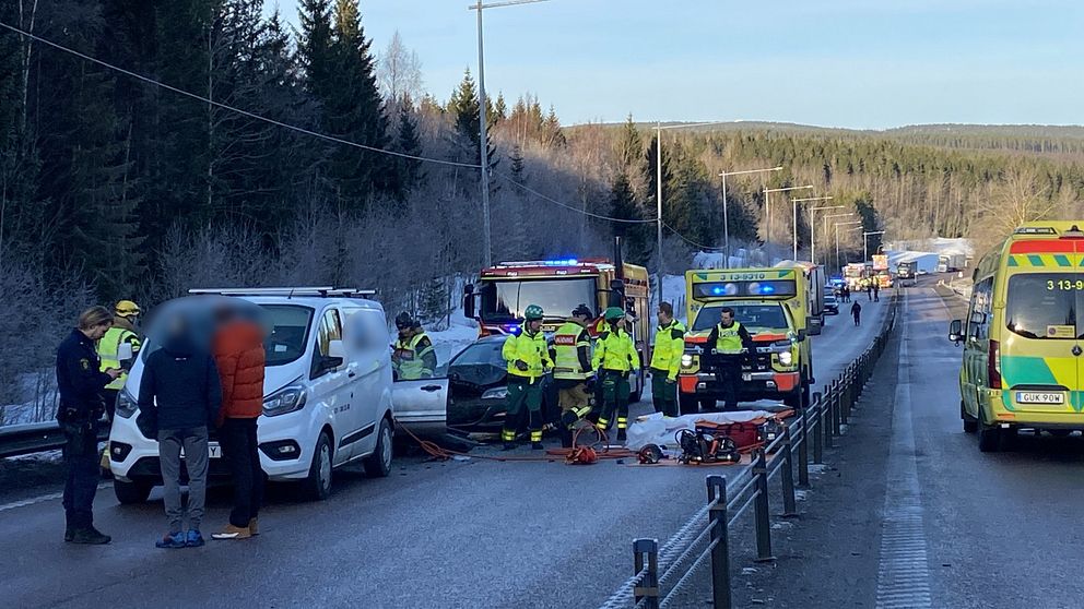 Räddningspersonal arbetar vid en olycksplats med flera ambulanser på en vinterväg.