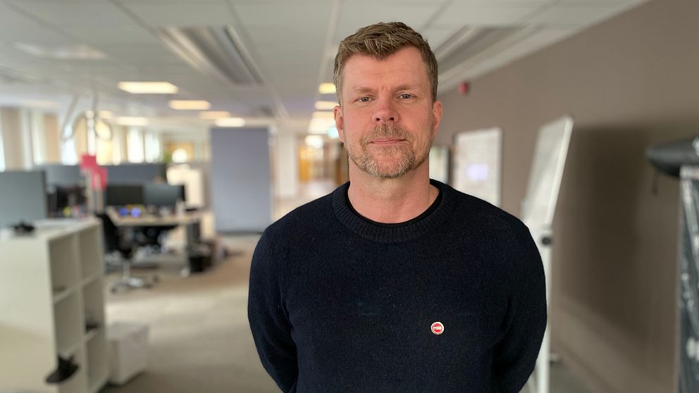 Petter Säterhed, funktionsansvarig på MSB, i svart tröja står i ett kontorslandskap med skrivbord och datorskärmar i bakgrunden.