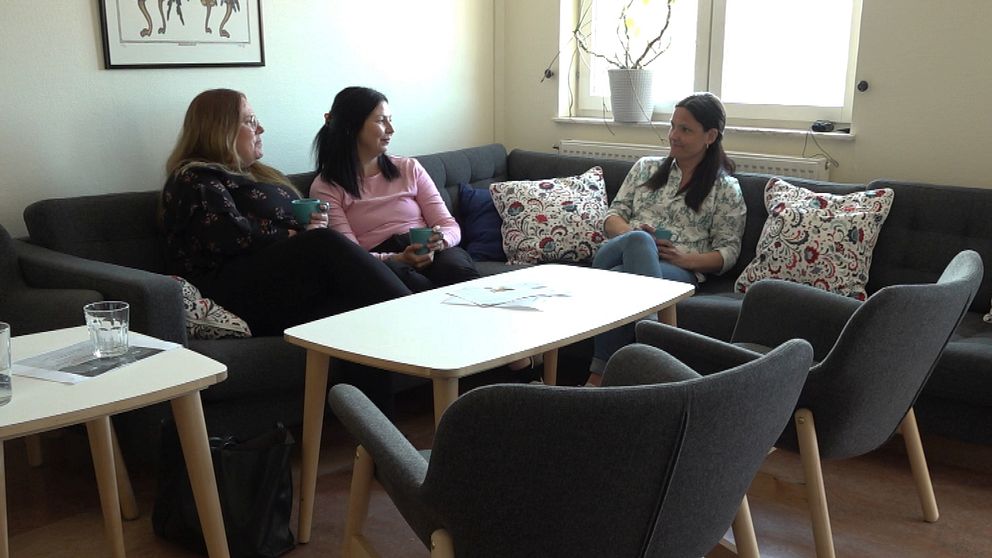 Tre kvinnor sitter och samtalar i en soffa