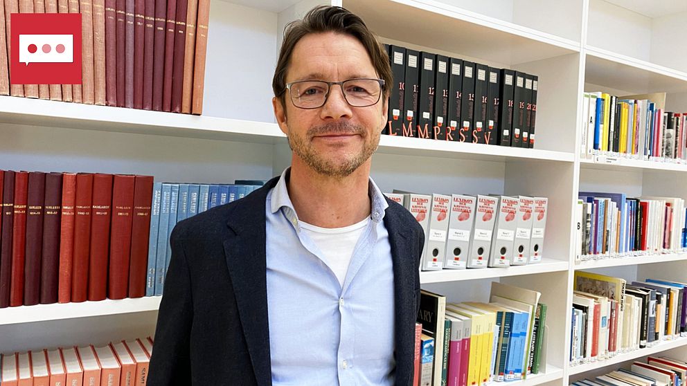Mats Tegmark står framför en vit bokhylla fylld med böcker.