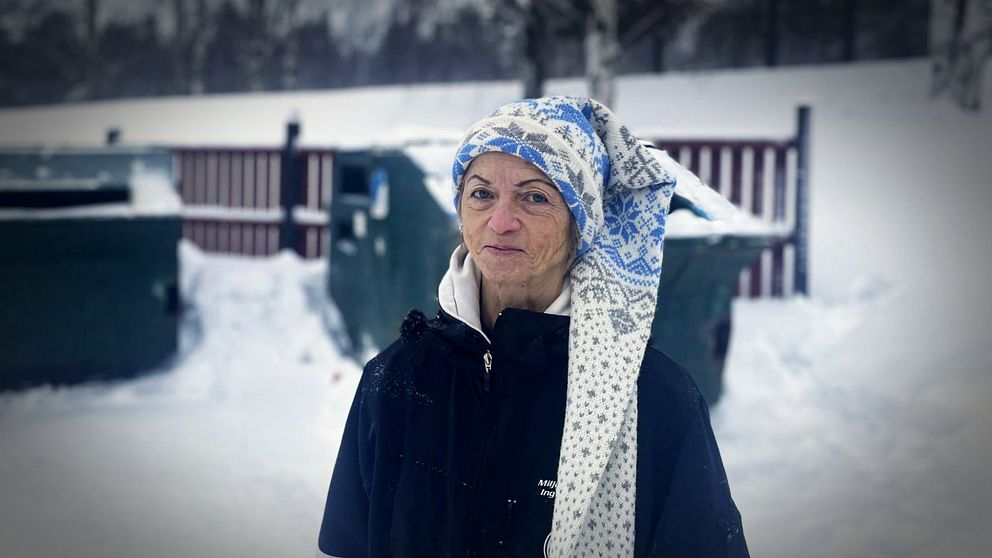 Inger Olofsson står framför gröna containrar på en återvinningsstation i Vännäs