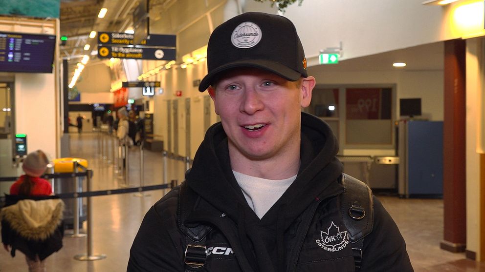 En glad kille i svart jacka och svart keps blir intervjuad på inne på flygplatsen på Frösön