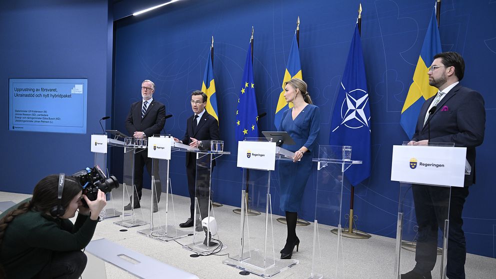 Presskonferens med svenska politiker framför EU och Nato-flaggor. Fotograf på plats.