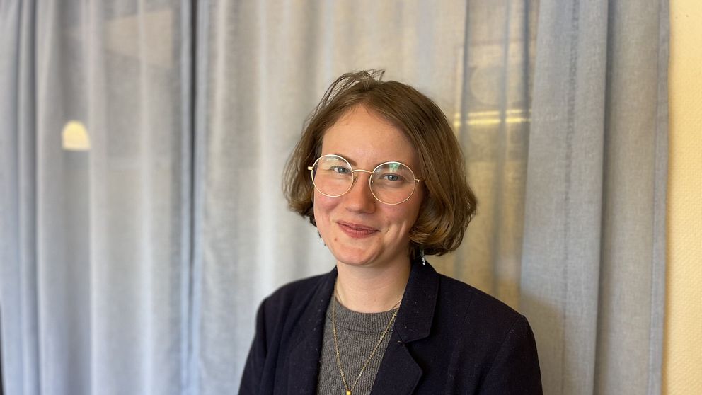 Irja Nilsson Nyberg står framför ljusgrå gardiner.