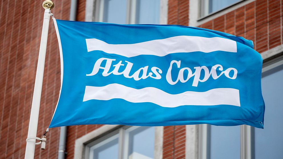 En flagga med Atlas Copcos logga på utanför en byggnad.