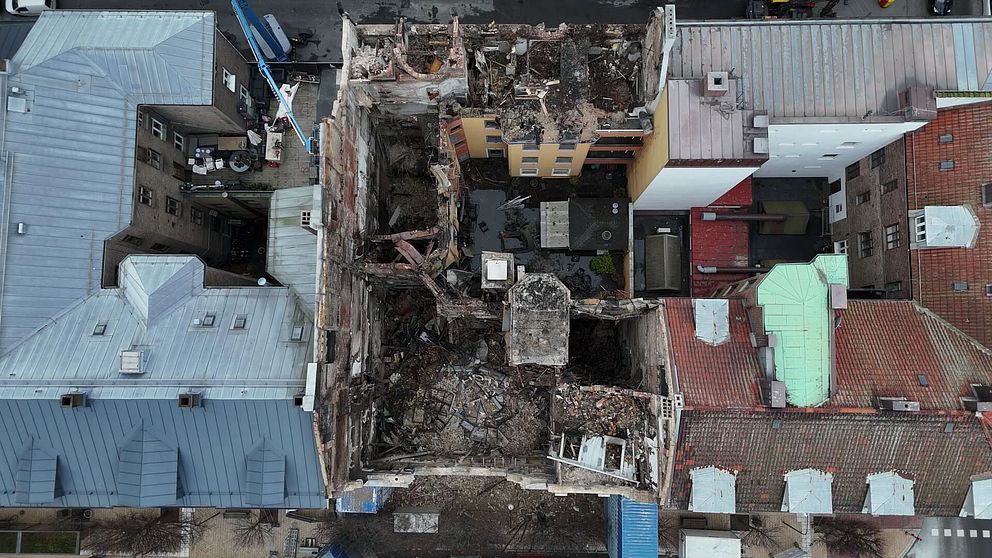 Översiktsbild av det ödelagda Hotell Kärnan i Helsingborg. Byggnaden är omgiven av intakta hus, vilket visar ruinerna av det kollapsade taket och den förstörda interiören efter branden.