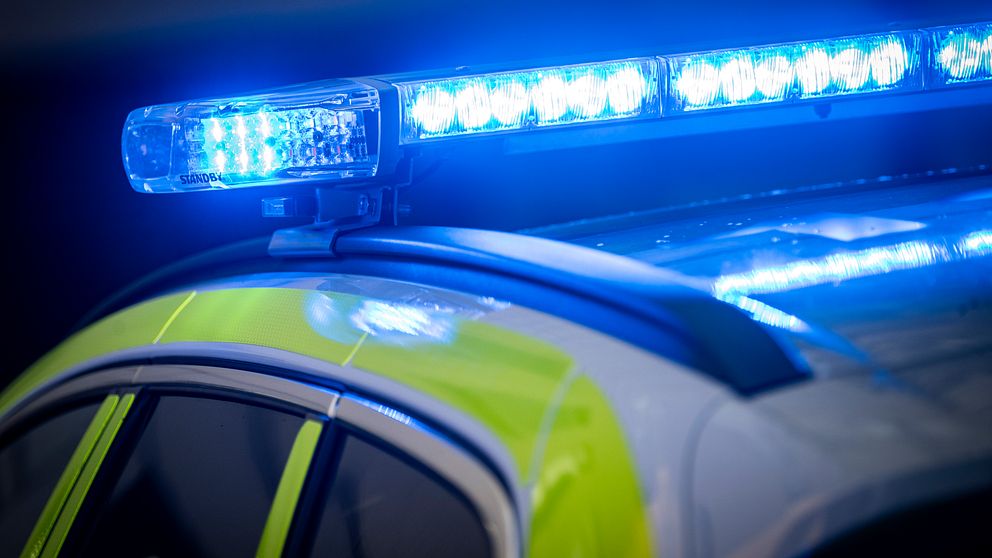 Polisbil med blåljus som är aktivt i mörker.