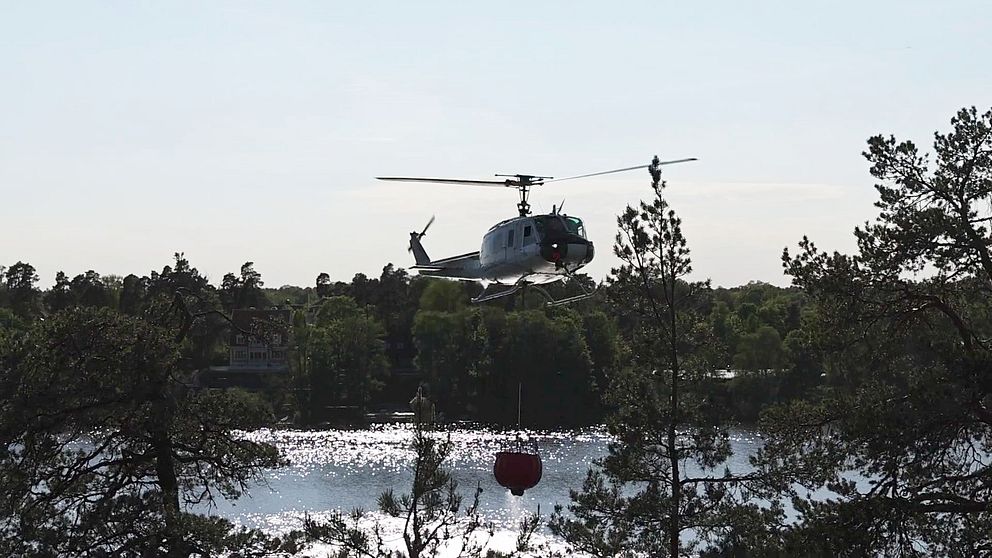 Helikopter hämtar vatten för att bekämpa skogsbrand i Sollentuna.