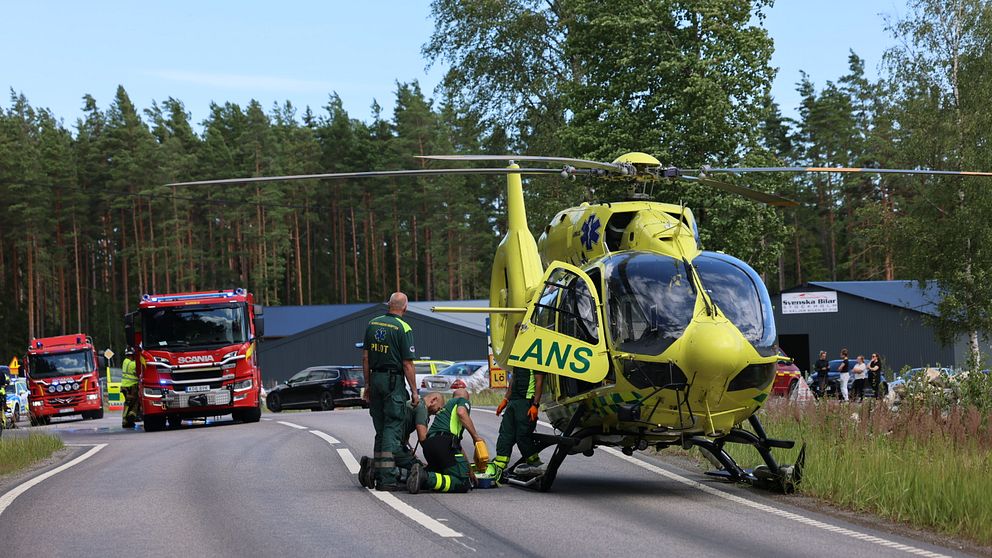 ambulanshelikopter och räddningspersonal vid olycksplats på väg