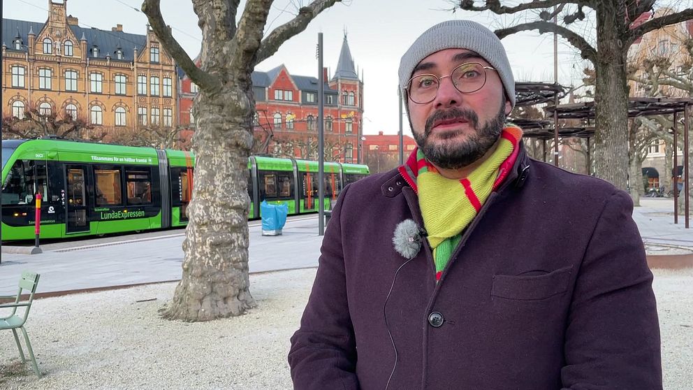 Saman Tondnevis, affärsområdeschef buss och spårvagn på Skånetrafiken, står framför en spårvagn på hållplatsen på Clemenstorget i Lund.
