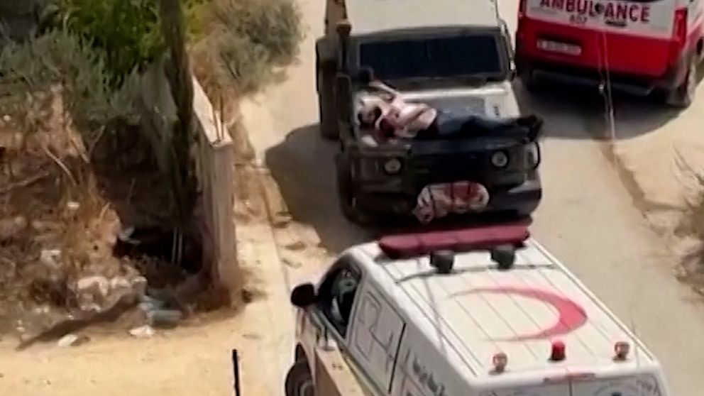 Skadad palestinsk man i Jenin på Västbanken ligger på motorhuven till en israelisk militärjeep