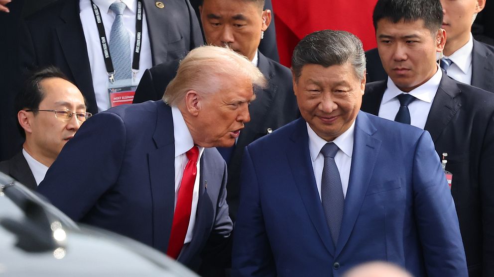 Donald Trump och Xi Jinping möts omgivna av säkerhetspersonal vid ett officiellt evenemang.
