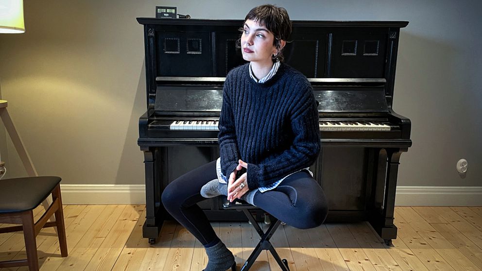 Linn Grins, artist och låtskrivare i bandet Raketklubben, sitter på en pall vid ett piano.