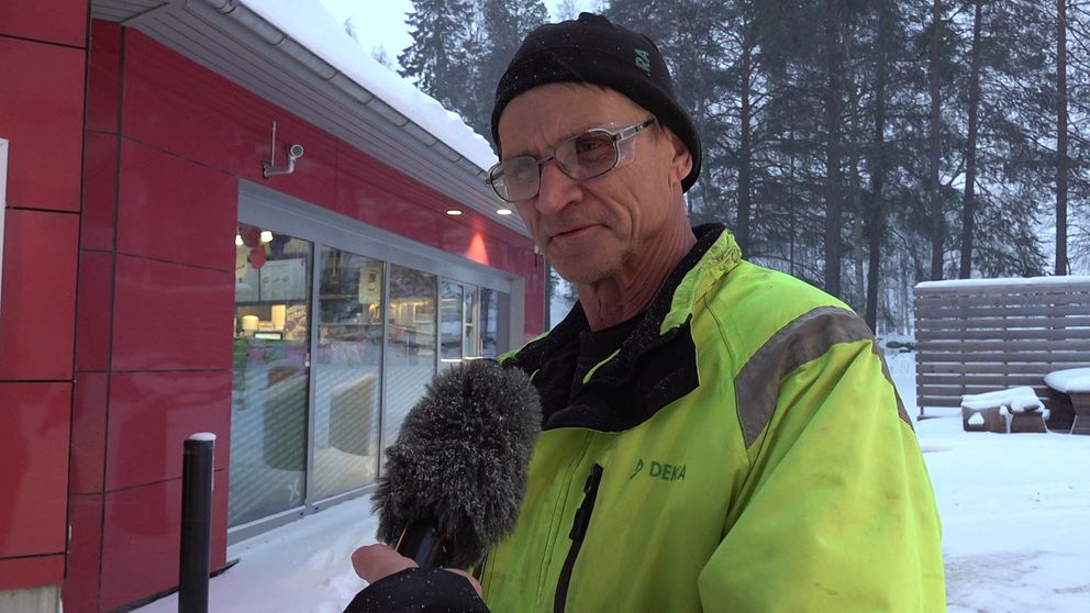 Man i gul jacka utanför bensinstation.