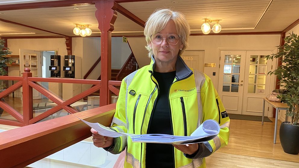 En kvinna står med papper i handen