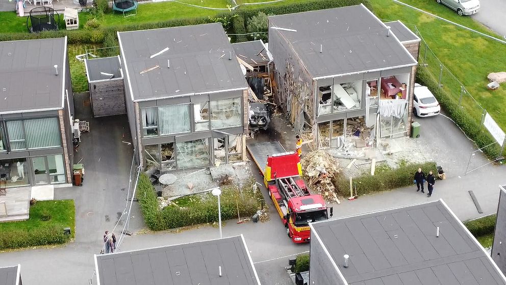 Skadade radhus med ett räddningsfordon i mitten.