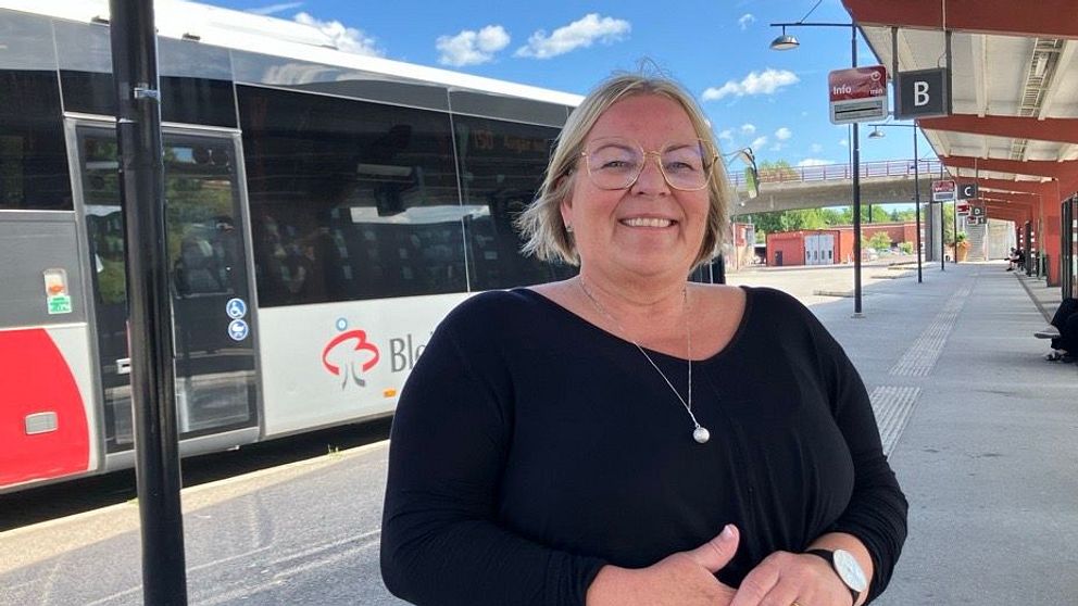Kvinna som står framför en buss