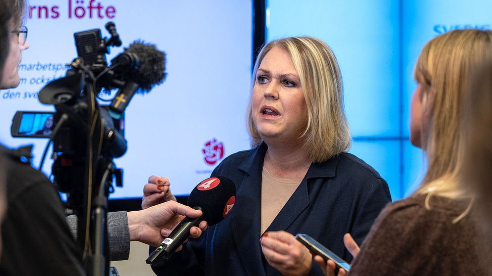 Lena Hallengren i riksdagen, intervjuas av journalister.