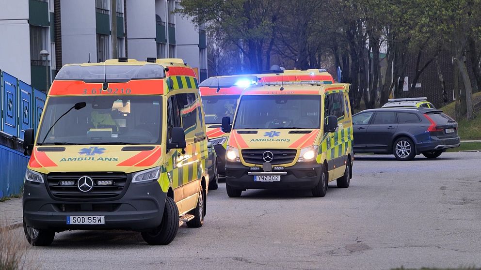 Två ambulansfordon parkerade vid en väg, ett med blinkande blåljus.
