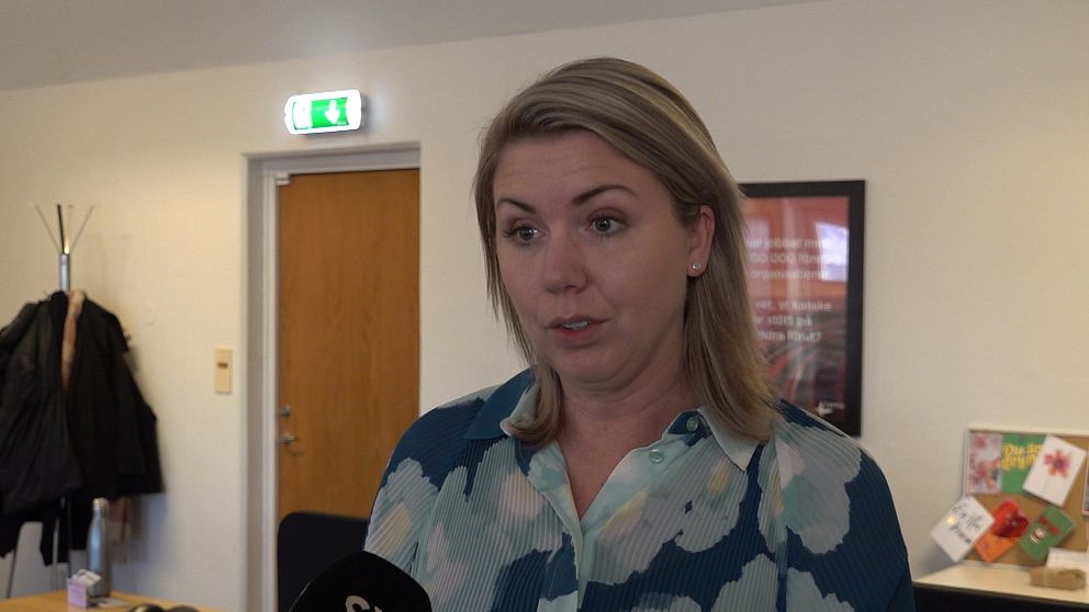 På bilden syns en blond kvinna med halvlångt blont hår och en blå blommig blus.