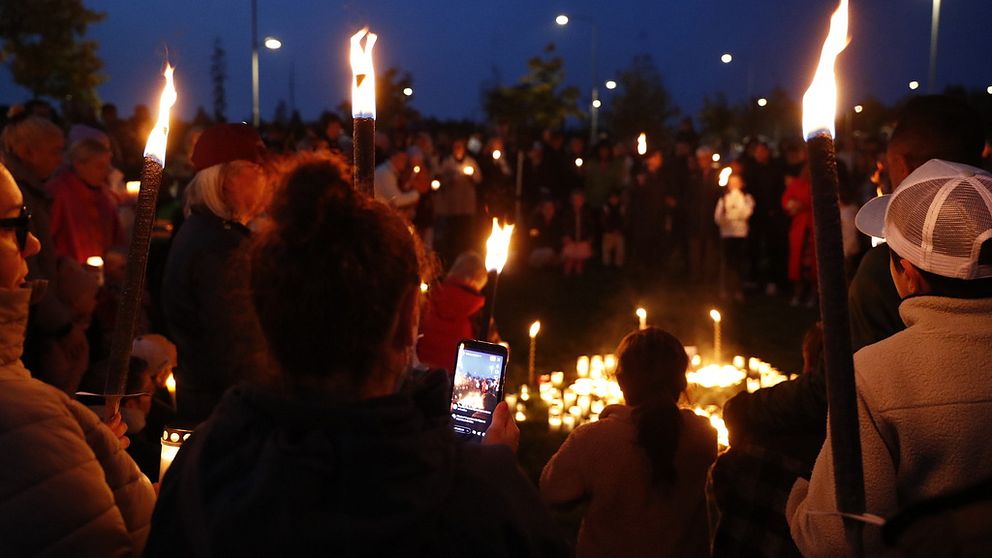 Personer med facklor i Fullerö Hage, i manifestation mot våldet.