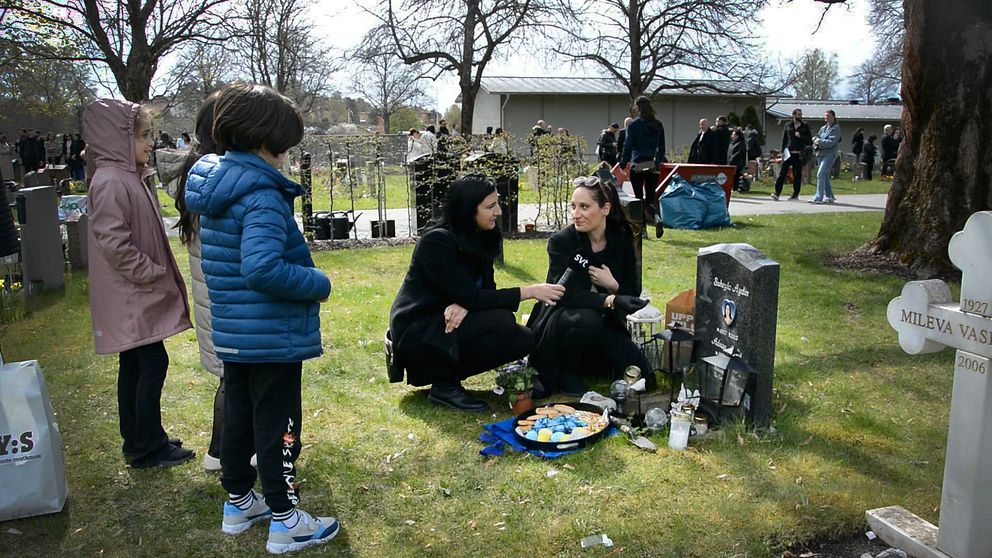 Annandag påsk firas på kyrkogården i Södertälje. En mamma sitter vid en grav med fika och godis, några barn står bredvid. .