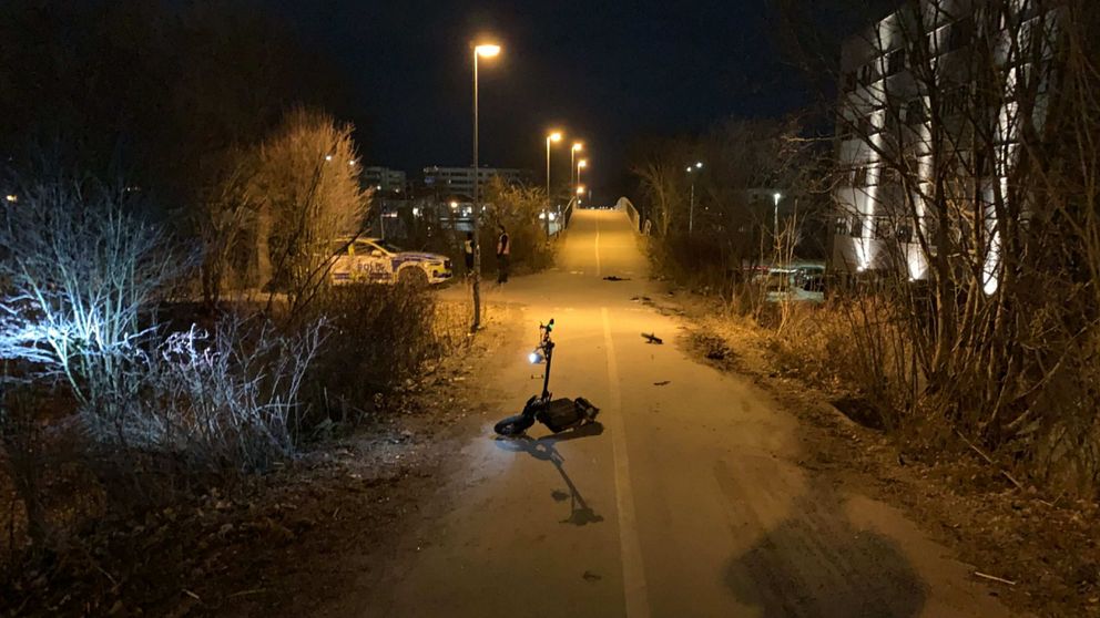 Trasig elsparkcykel på cykelbana, nattetid,  i gul/orange-beslysning
