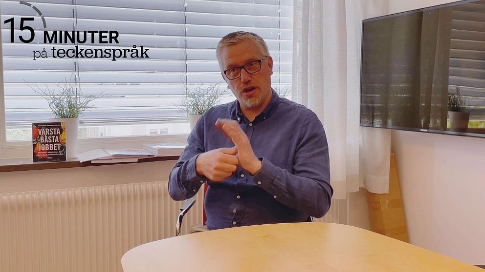 Roger Holmström har en blå skjorta på sig och sitter vid ett bord. Bakom honom finns ett fönster och till höger finns en tv.