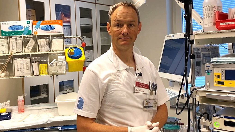 Gert Nestler, chef på kirurgkliniken i Falun, iklädd vita arbetskläder, sitter bland sjukvårdsutrustning.