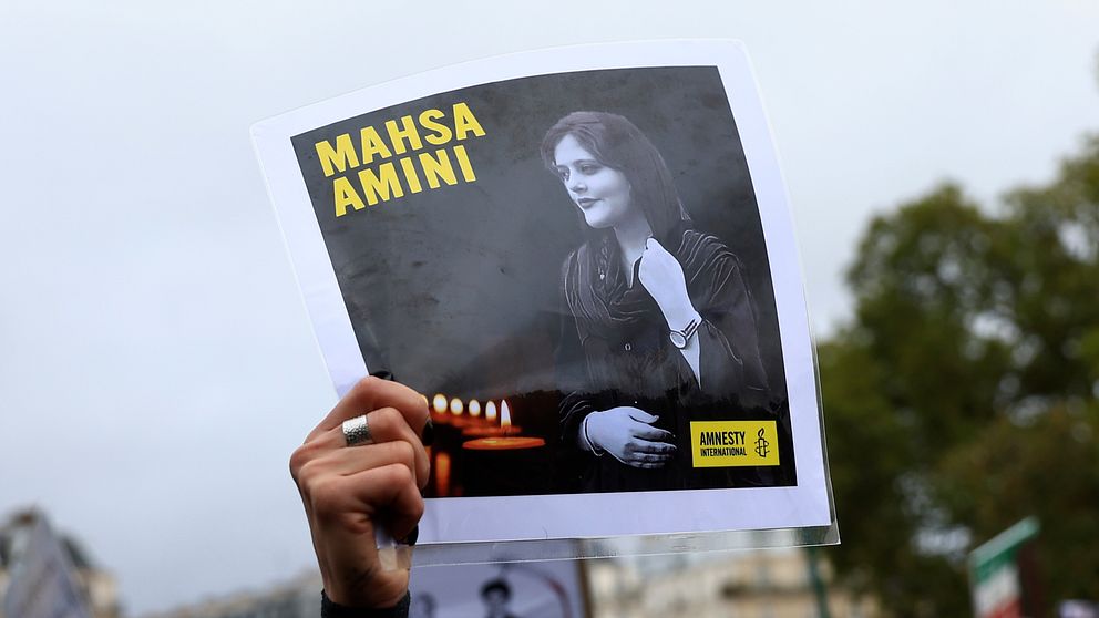 En demonstrant håller upp ett porträtt av Mahsa  Zhina Amini under en demonstration i Paris till stöd för de iranska protesterna efter Aminis död.