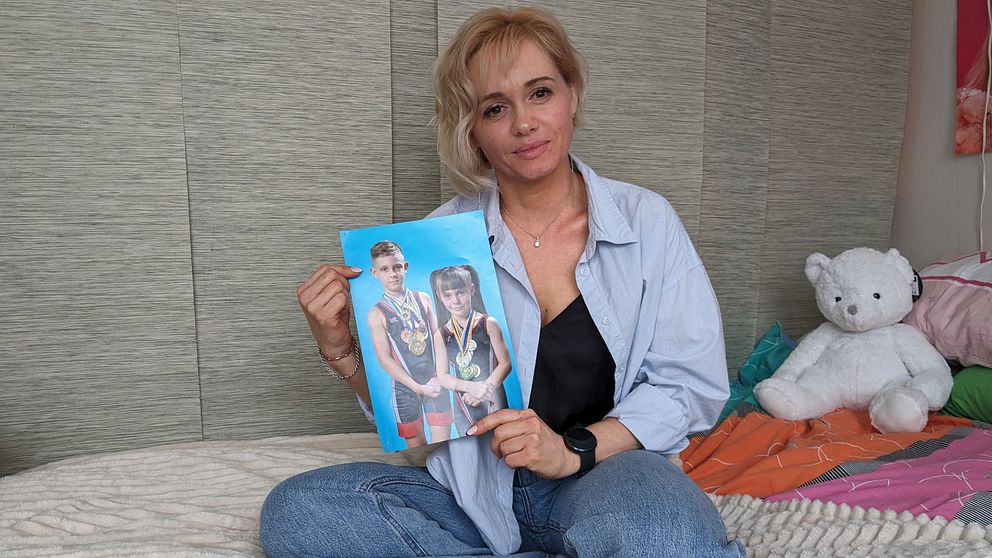 Olga Pankova sitter på sin och dottern Mariams säng. I famnen håller hon en bild på Mariam och Michael i brottarklädsel.
