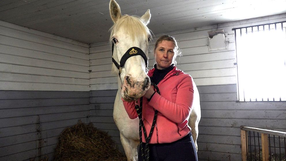 Magdalena Rubensson Zäll, ridskolechef på Tibro Ryttarförening, håller i den vita hästen Betty.