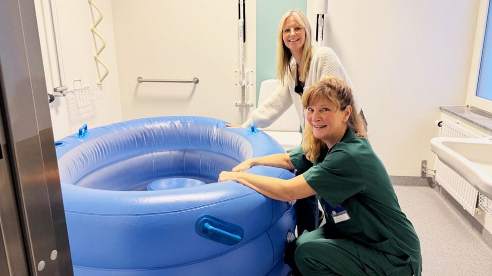 en chef och en barnmorska sitter vid en förlossningspool i ett badrum