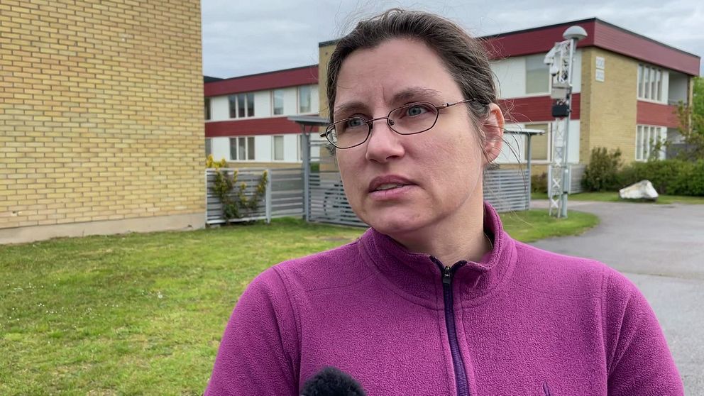 Person i lila tröja intervjuas utomhus framför en byggnad.