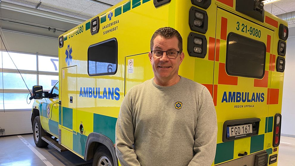 En man med glasögon står framför en ambulans inne på ambulanscentralen i Uppsala