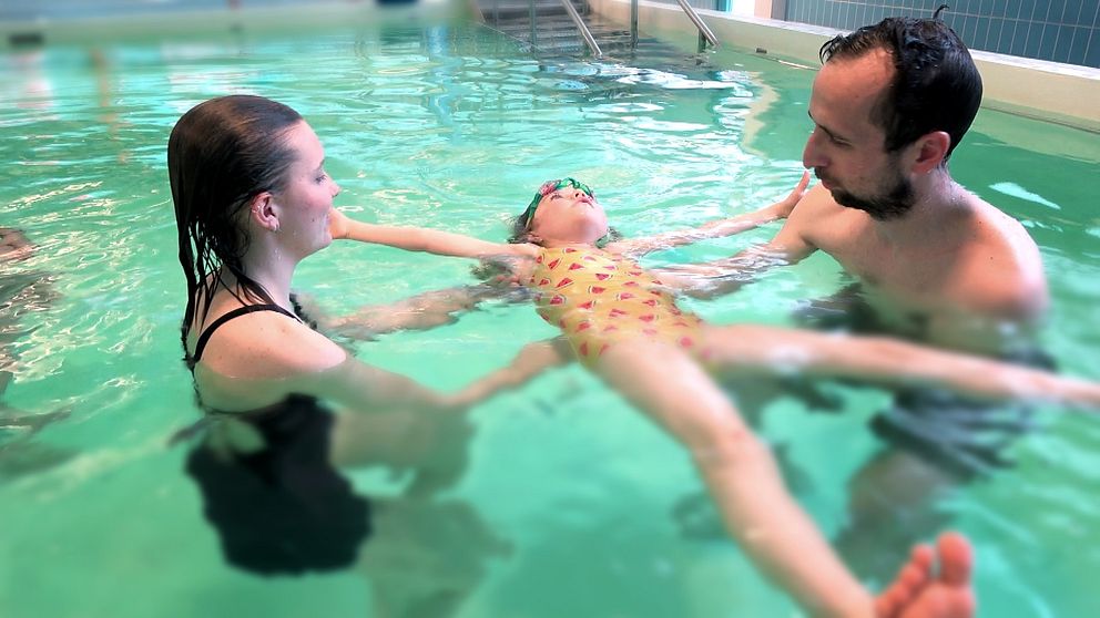 En pappa och hans barn får lära sig att simma i en pool.