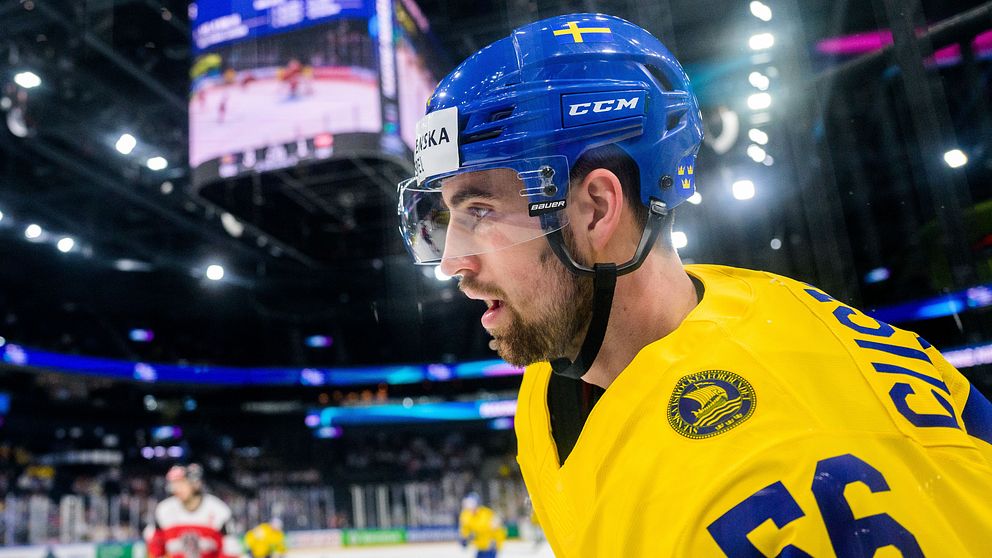 Ishockeyspelare i gul tröja på isen under match mot lag i rödvit dräkt.