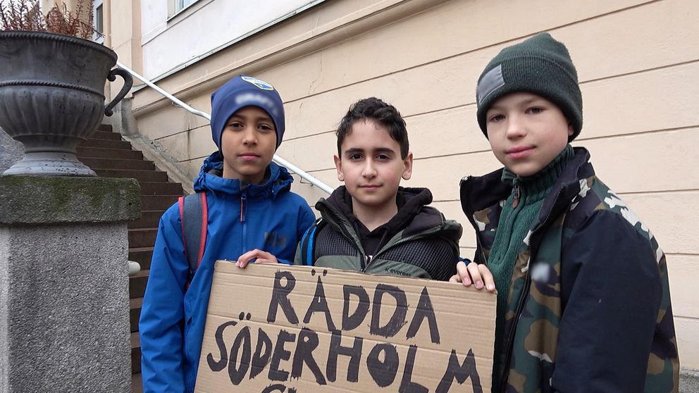 Tre pojkar framför plakat med texten: ”Rädda Söderholmsskolan”