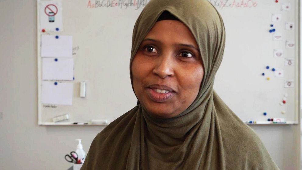 Halimo Ahmed, en kvinna med mörkgrön slöja, står framför en whiteboard i ett klassrum.