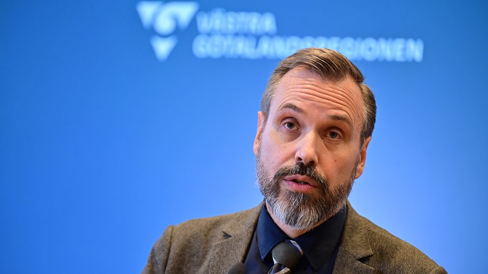Person i kavaj framför Västra Götalandsregionens logotyp.