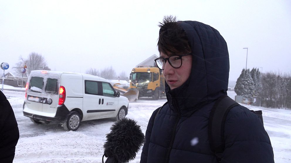 En kille står ute i snön med luvan på huvudet.