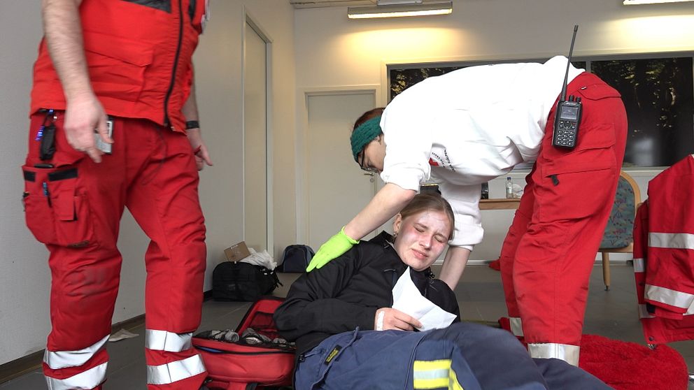 En medlem från Röda Korset hjälper en skadad tjej att lägga sig på en brits under en krisberedskapsövning.