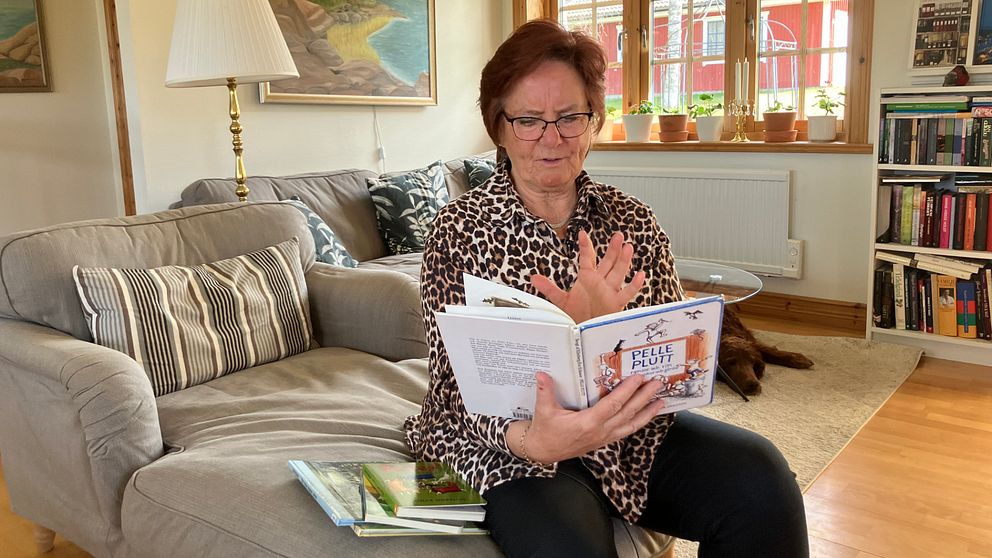 Person sitter i soffa med bok, omgiven av inredning och bokhyllor i ett vardagsrum.